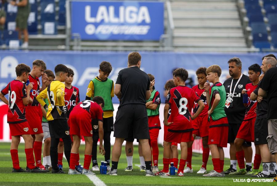 Jugadores de la Academia del Rayo Vallecano recibiendo instrucciones en un estadio de LaLiga